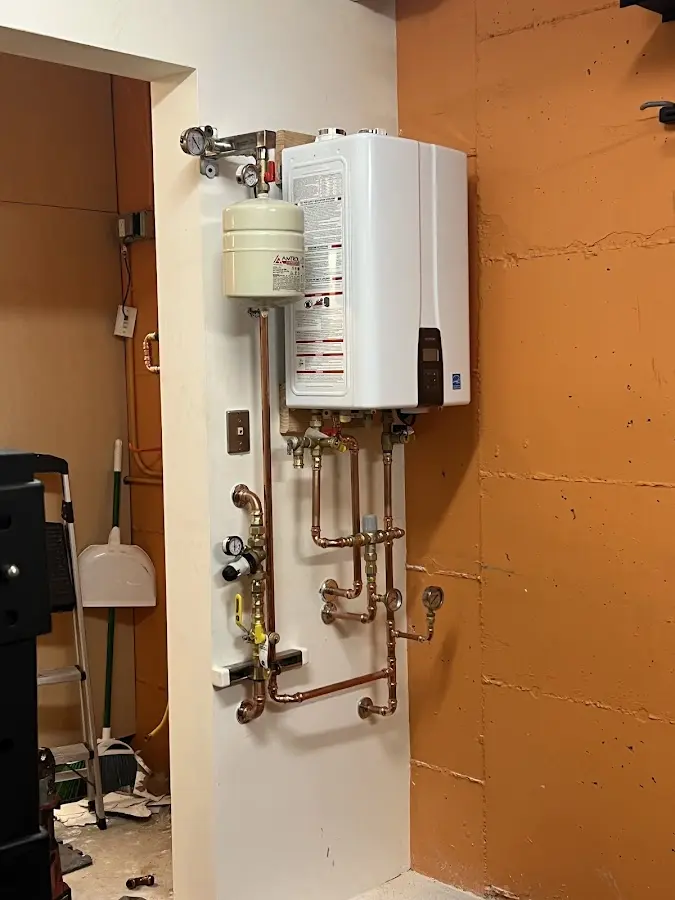 Plumbing technician inspecting water heater connections in Greenfield